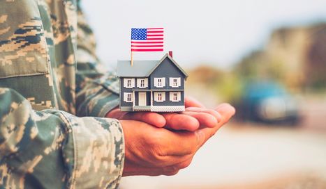 Person in military holding miniature home in hands